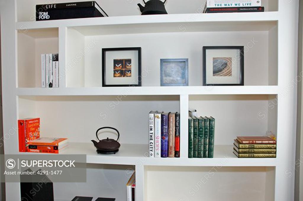 Pictures and books on modern white shelves SuperStock