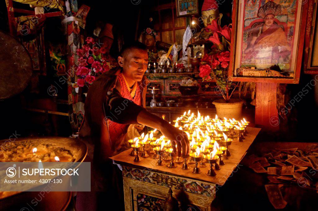Monk Lighting Candles SuperStock