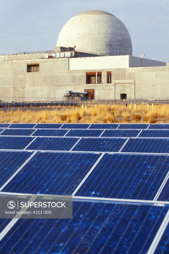 Solar panels at White Bluffs Solar Station with nuclear power plant in