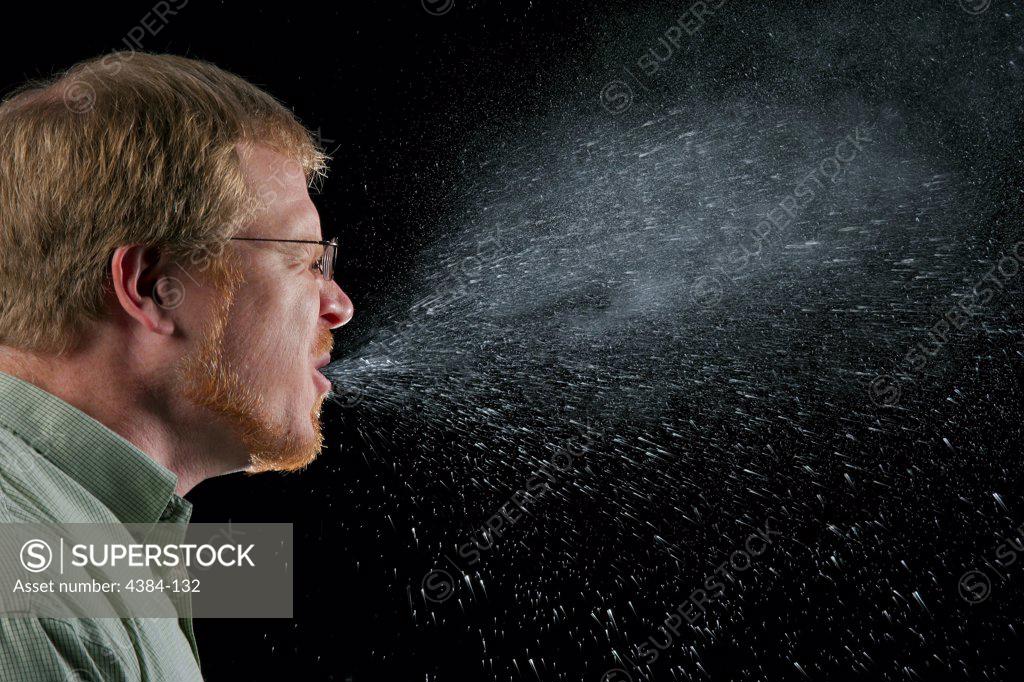 A sneeze in progress, revealing the plume of salivary droplets as they
