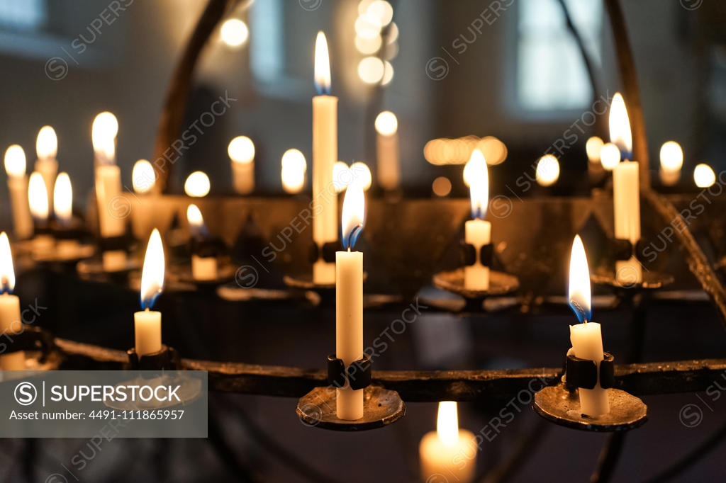 Golden flame of candles in candlesticks glowing in darkness in Oslo Cathedral;Candles burning in