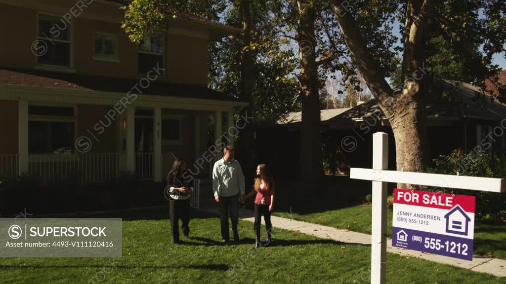 WS Young couple shaking hands with real estate agent and hugging in