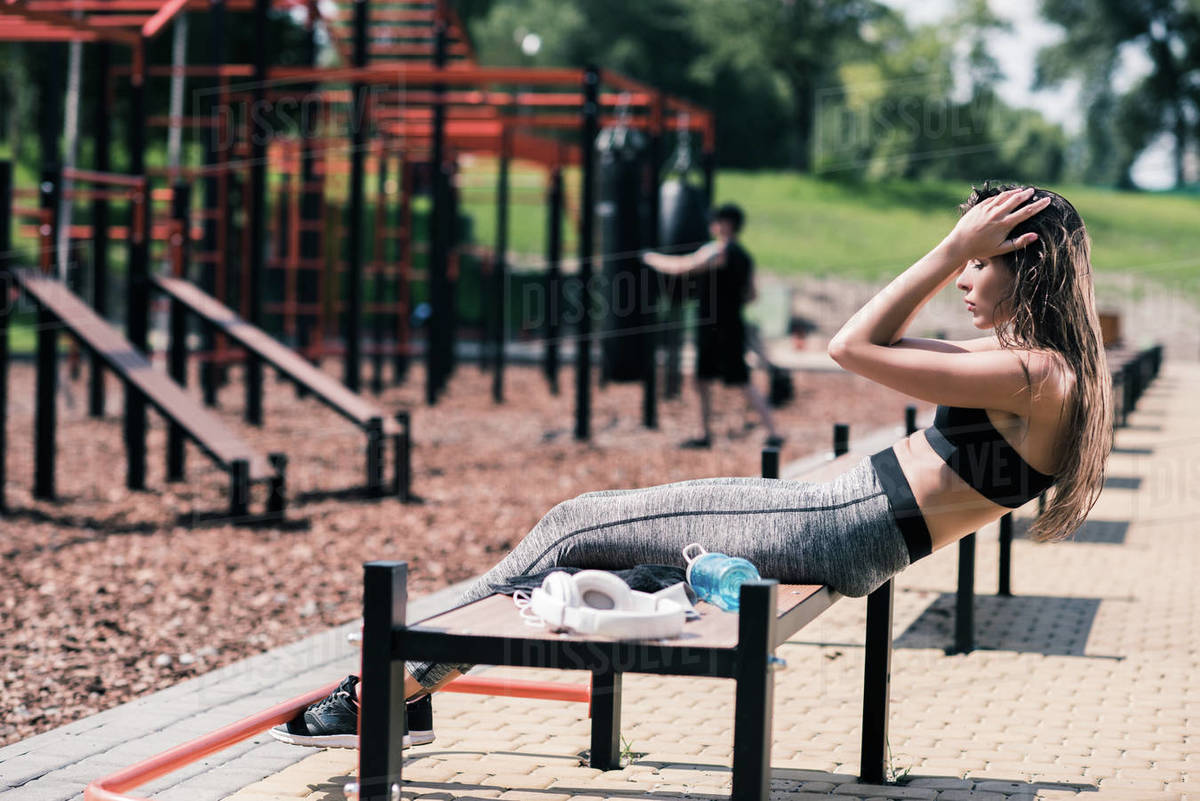 Side view of young woman doing abs exercises on bench Stock Photo
