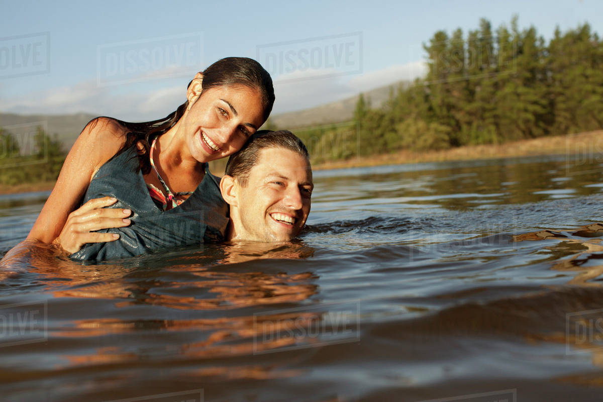 Portrait of smiling couple swimming in lake Stock Photo Dissolve