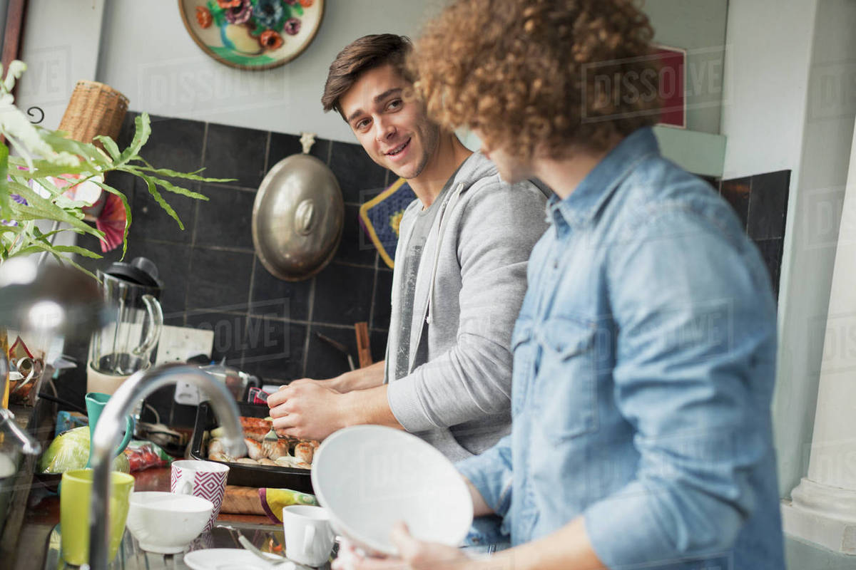 Young men roommates cooking and doing dishes in kitchen Stock Photo Dissolve
