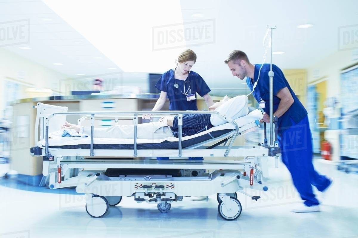 Two medics pushing gurney in hospital emergency room Stock Photo Dissolve