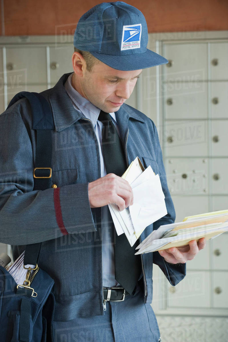Male postal worker looking at mail Stock Photo Dissolve