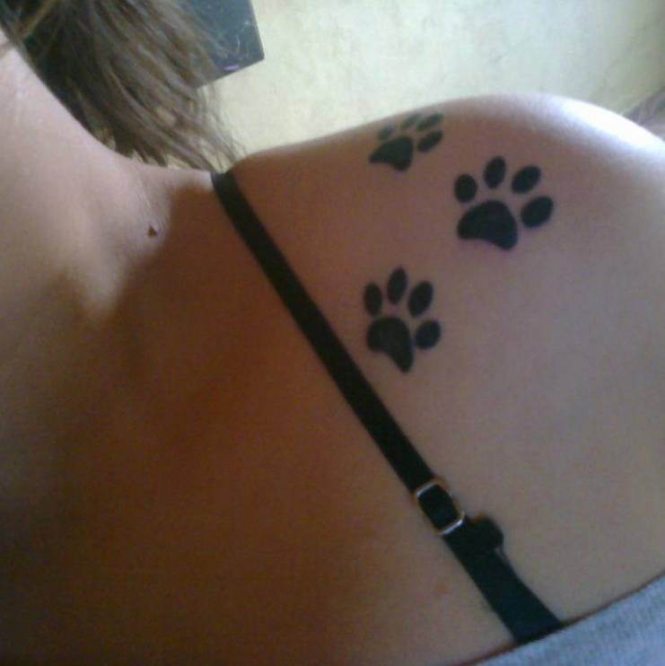 Shoulder tattoo of three dog paws.