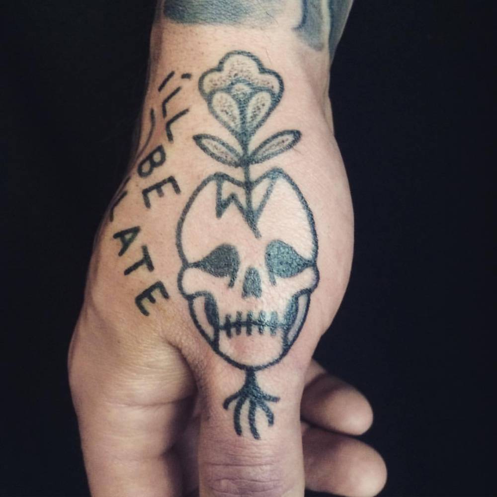 Hand poked skull and flower tattoo on the right hand.