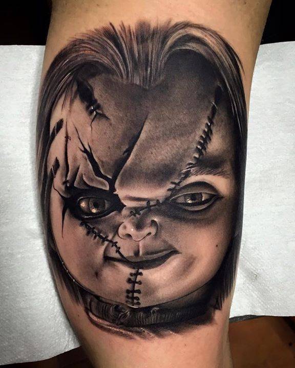 Black and grey Chucky tattoo on the left inner arm.