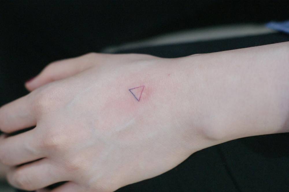 Hand poked triangle spectrum tattoo on the hand.