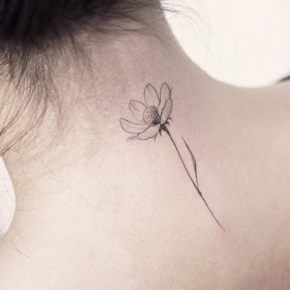 Fine line flower tattoo on the upper back.