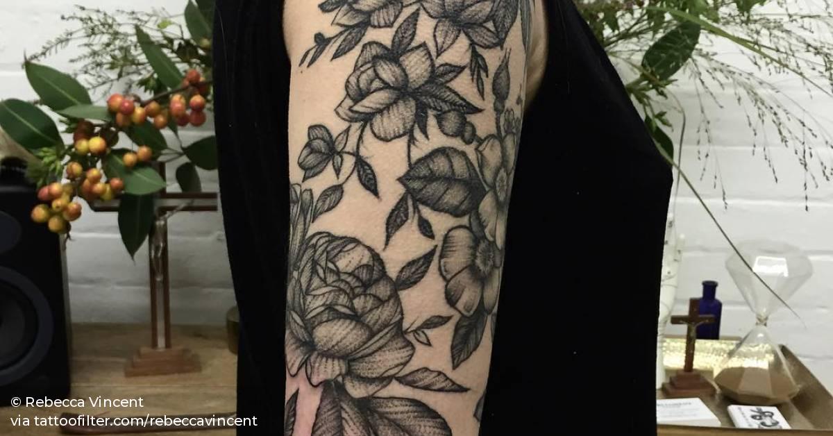 Blackwork style floral tattoo on the right upper arm.