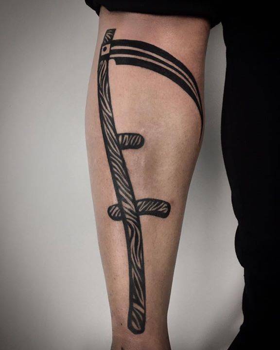 Scythe tattoo on the left calf.