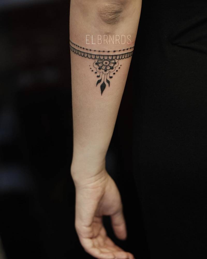 Ornamental armband tattoo on the left forearm.