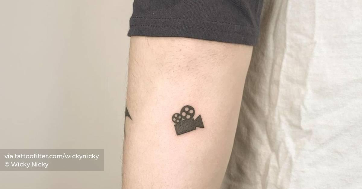 Minimalist film camera tattoo on the inner forearm