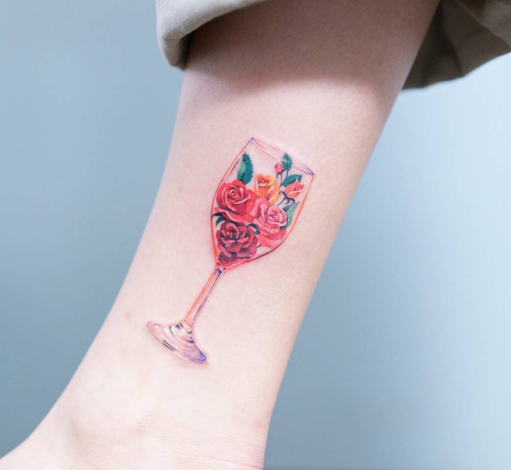 Floral wine glass tattoo on the ankle.