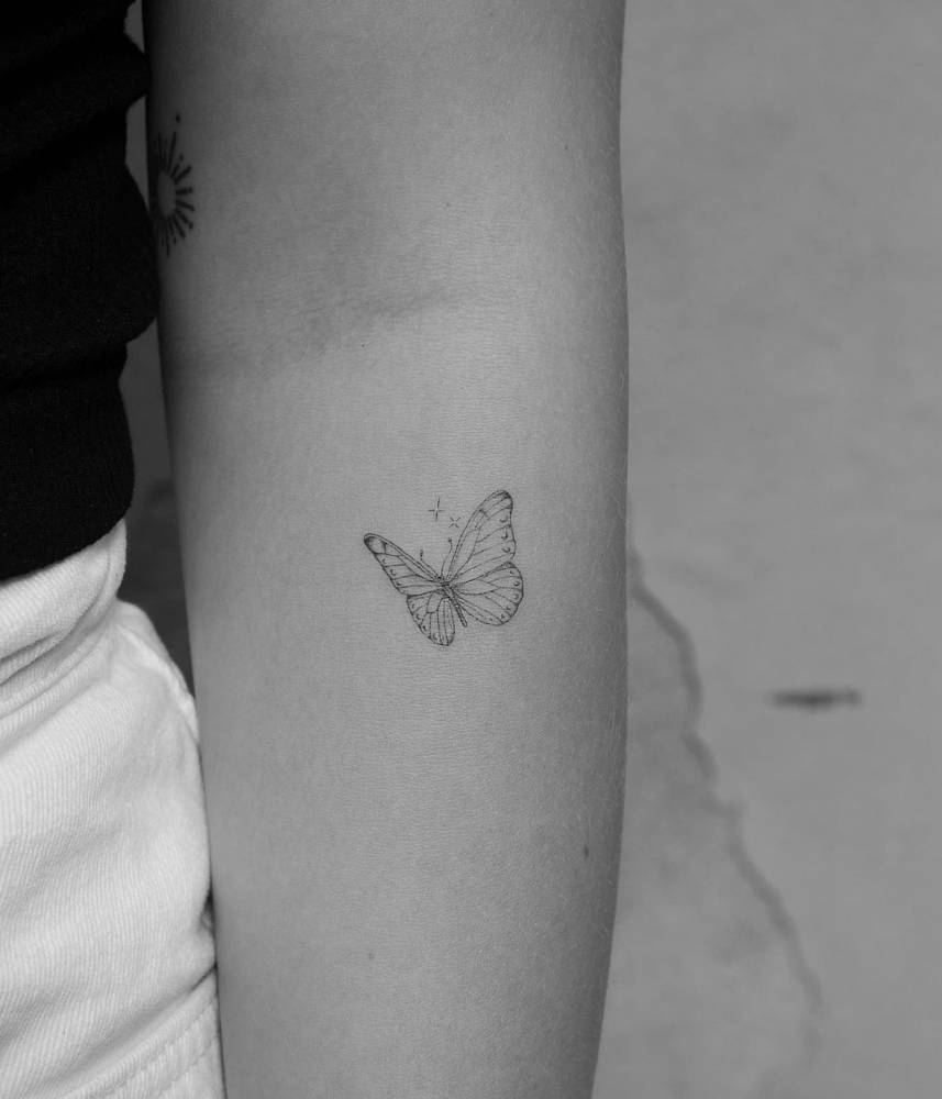 Fine line butterfly tattoo on the inner forearm