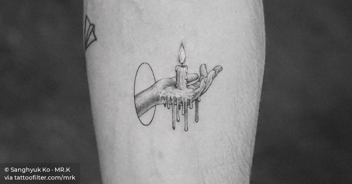 Hand holding a candle tattoo on the inner forearm.