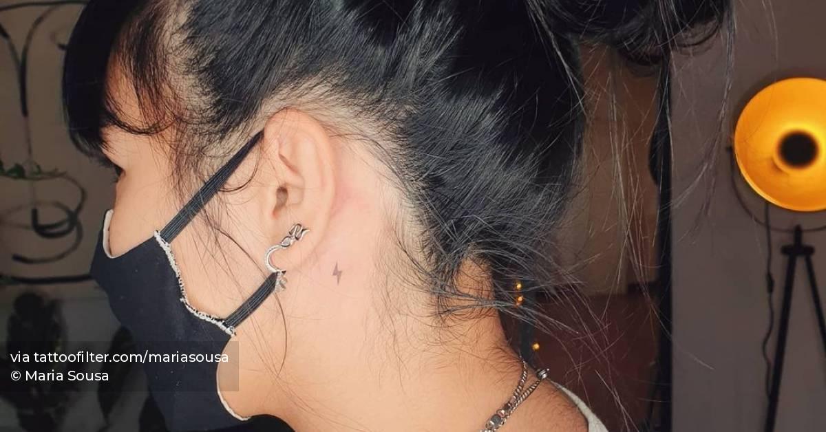 Minimalist lightning bolt tattoo behind ear.