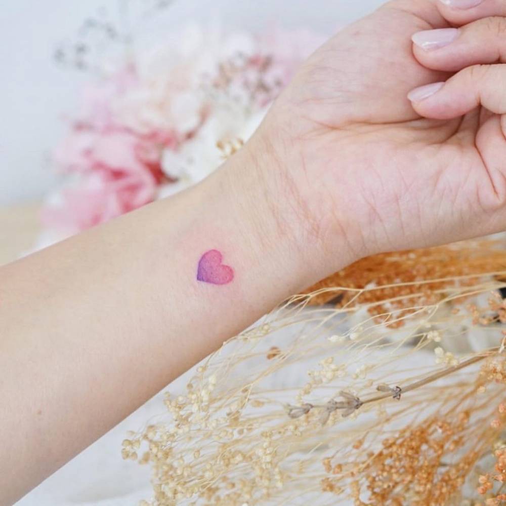 Minimalist heart tattoo on the wrist.