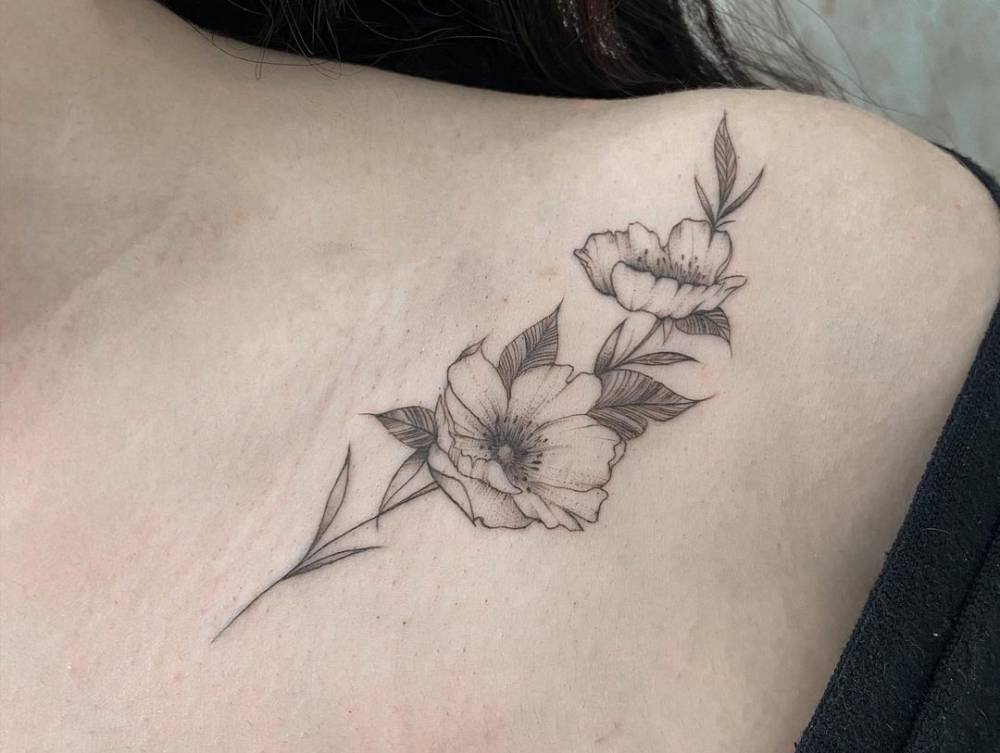 FIne line flower tattoo on the collarbone.