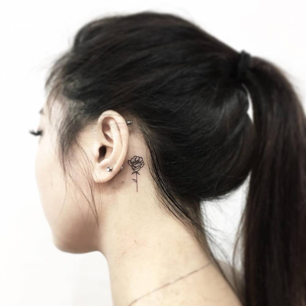 Fine line rose tattoo on the back of the left ear.