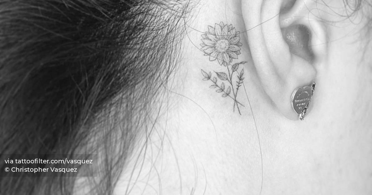 Microrealistic sunflower tattooed behind the ear.