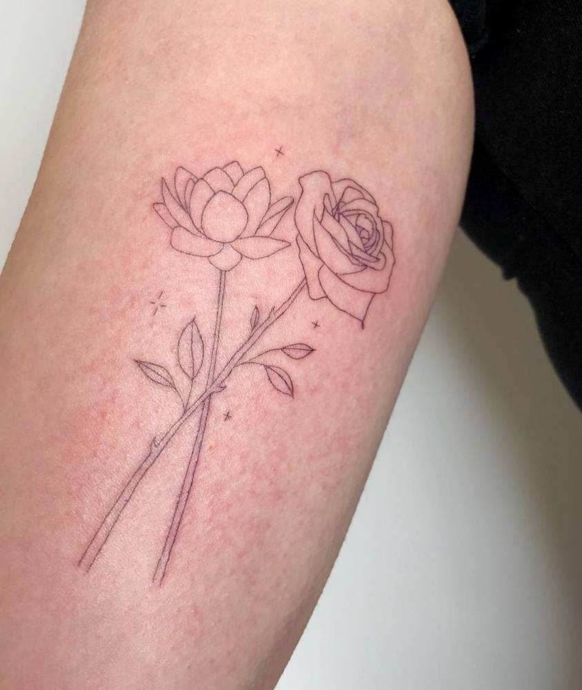 Lotus and rose flowers tattooed on the inner forearm,