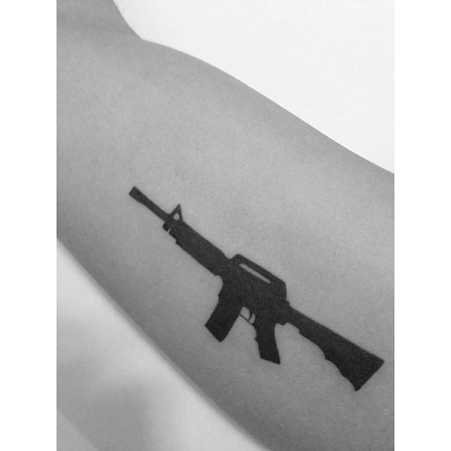 Minimalistic style rifle tattoo done on the inner arm.