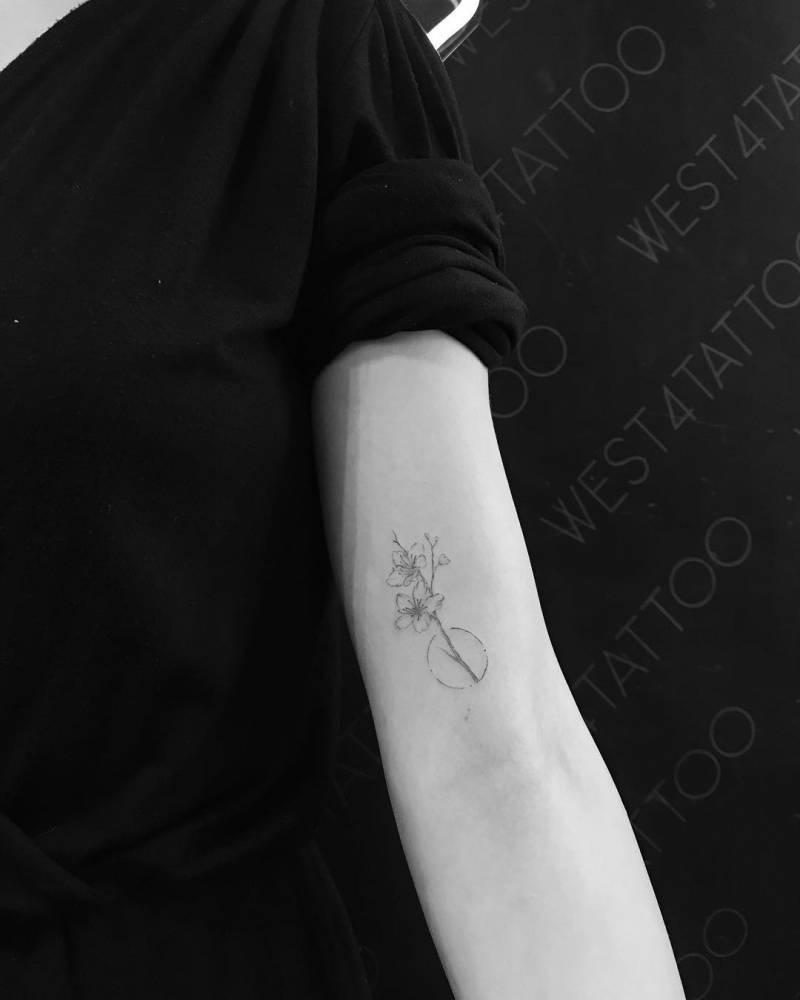 Cherry blossom branch tattoo on the inner arm.
