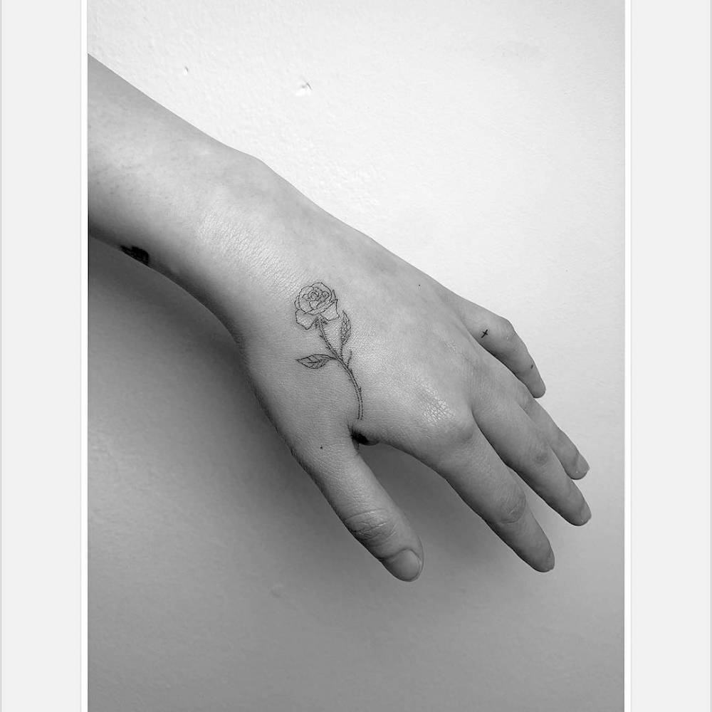 Fine line rose tattoo located on the hand.