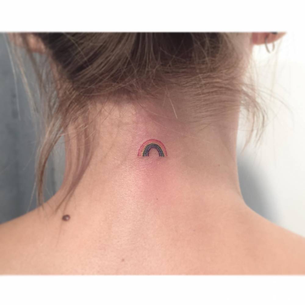 Minimalistic rainbow tattoo located on the back of the