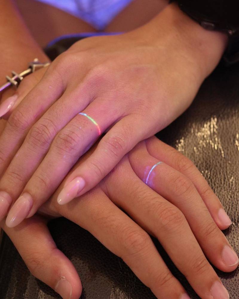 Matching UV ink rings tattooed for couple.