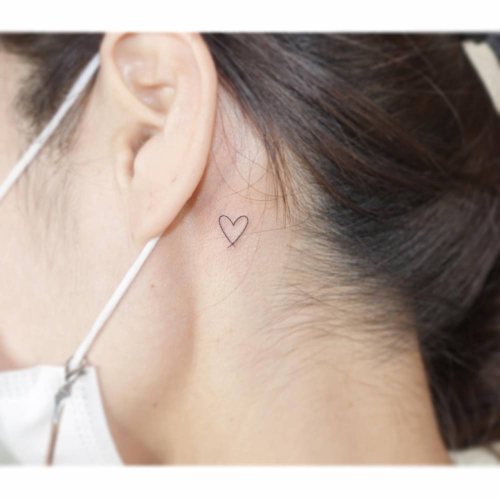 Minimalistic heart tattoo located behind the ear.