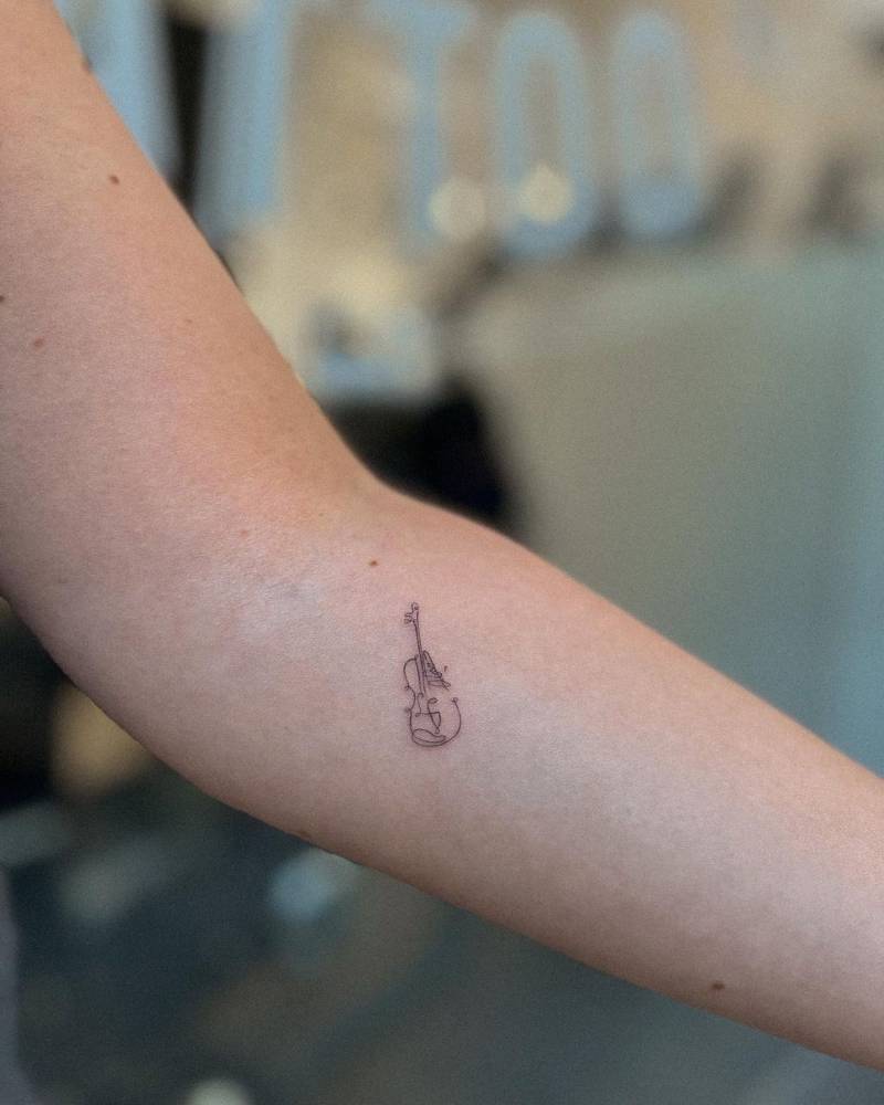 One line violin tattoo placed on the inner forearm,