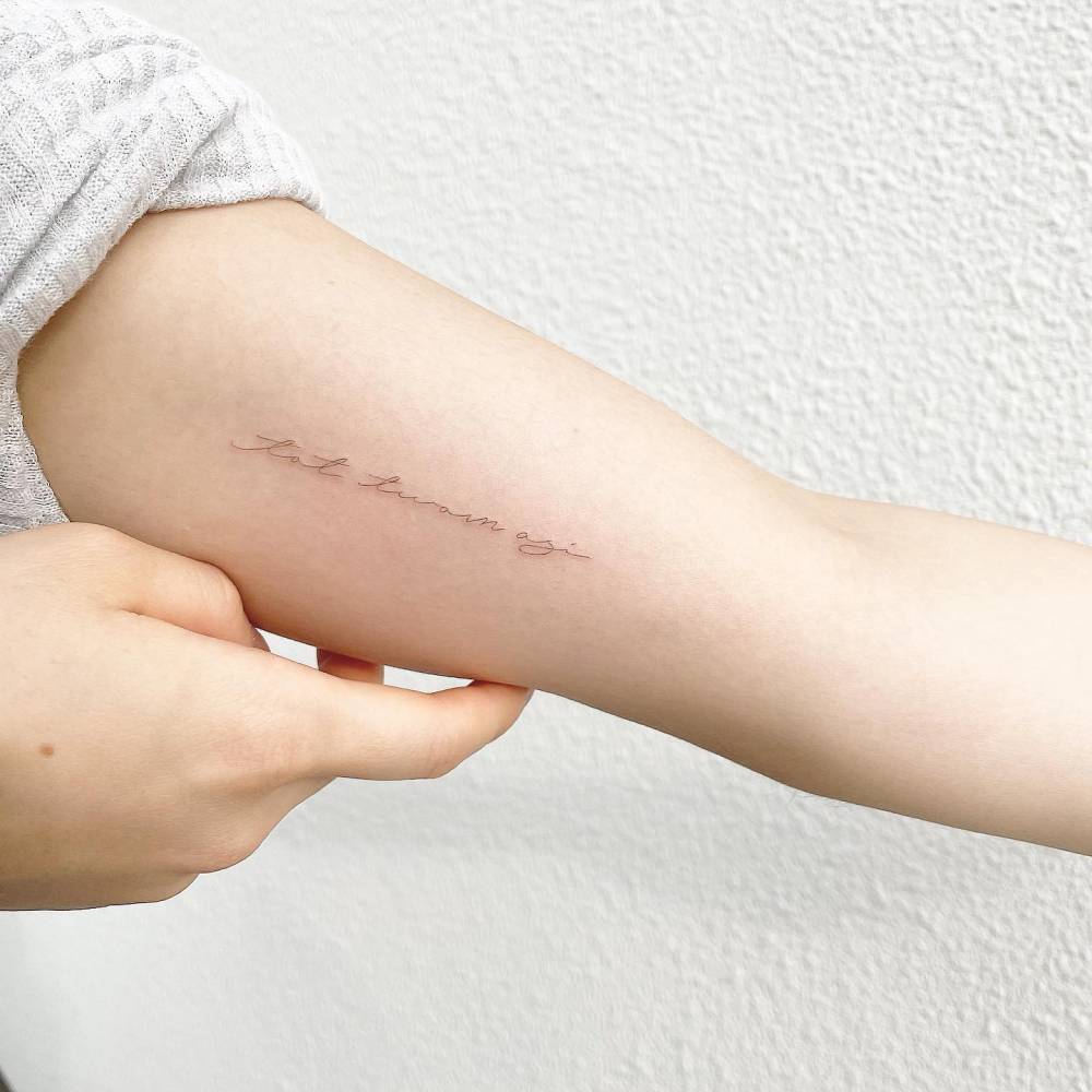 Handwritten lettering tattoo located on the inner arm.
