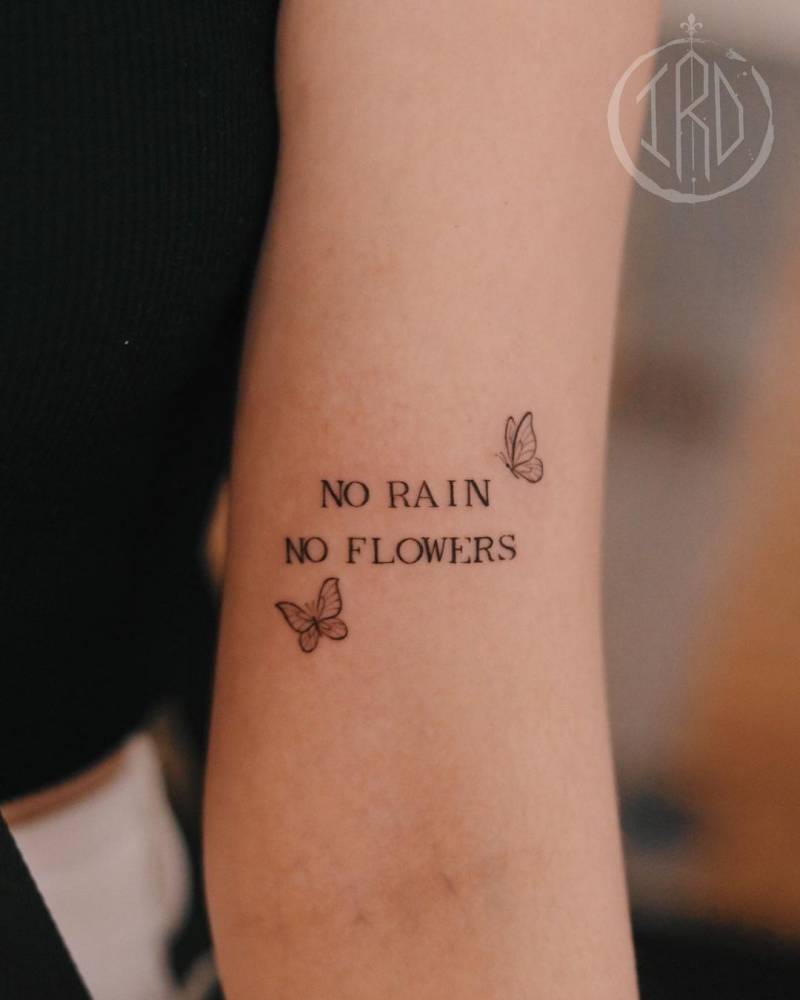 "No rain, no flowers" lettering tattoo located on the