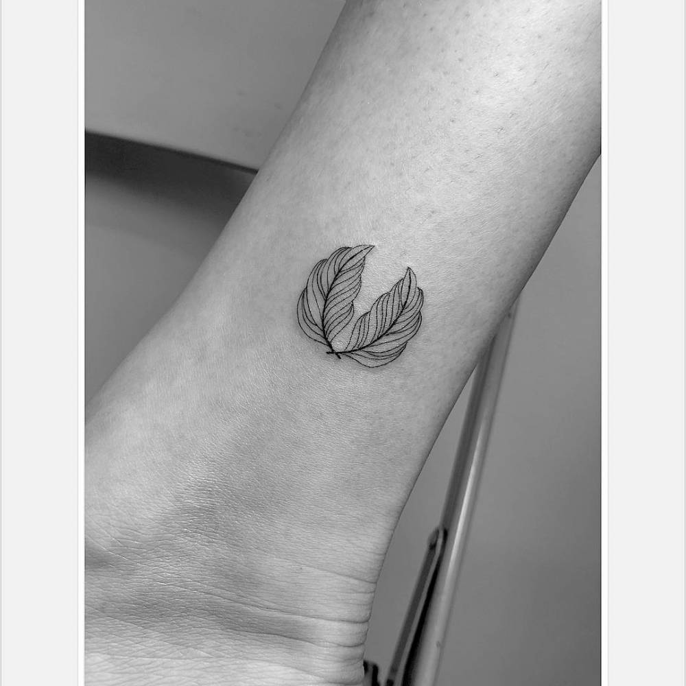 Fine line feathers tattoo located on the ankle.