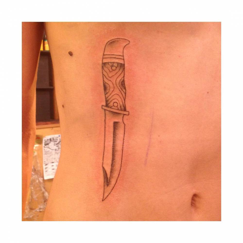 Knife tattoo located on the rib.
