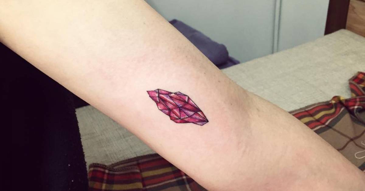 Ruby birthstone tattoo on the left inner arm.