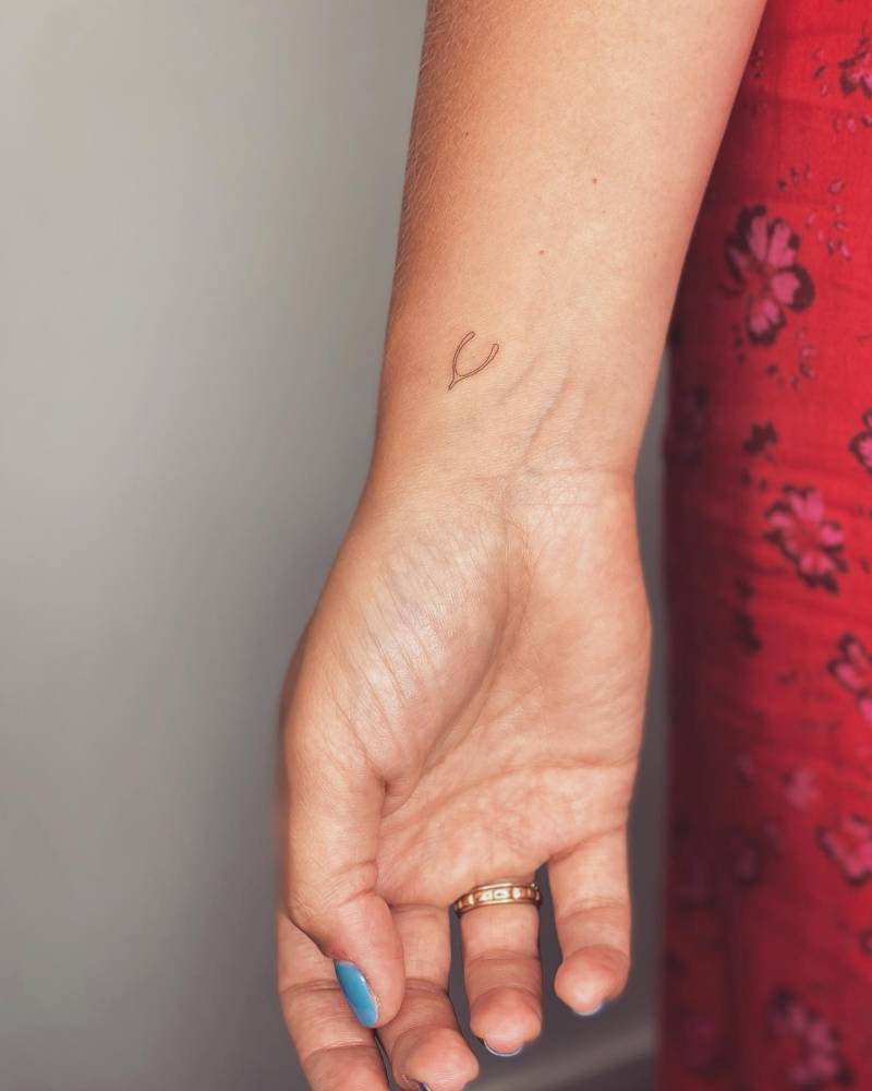 Fine line wishbone tattoo located on the wrist,