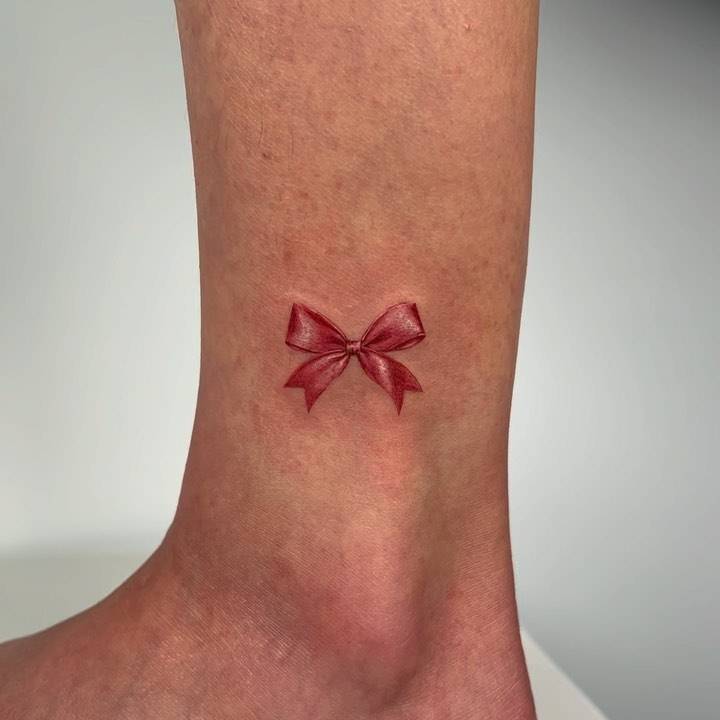 Microrealistic ribbon tattoo located on the ankle.