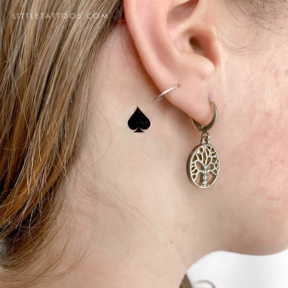Spade suit temporary tattoo located behind the ear.
