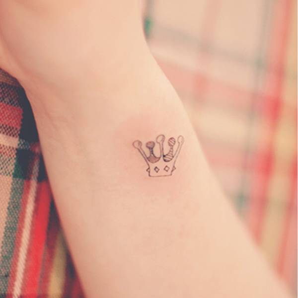 Small crown tattoo on the right inner wrist.