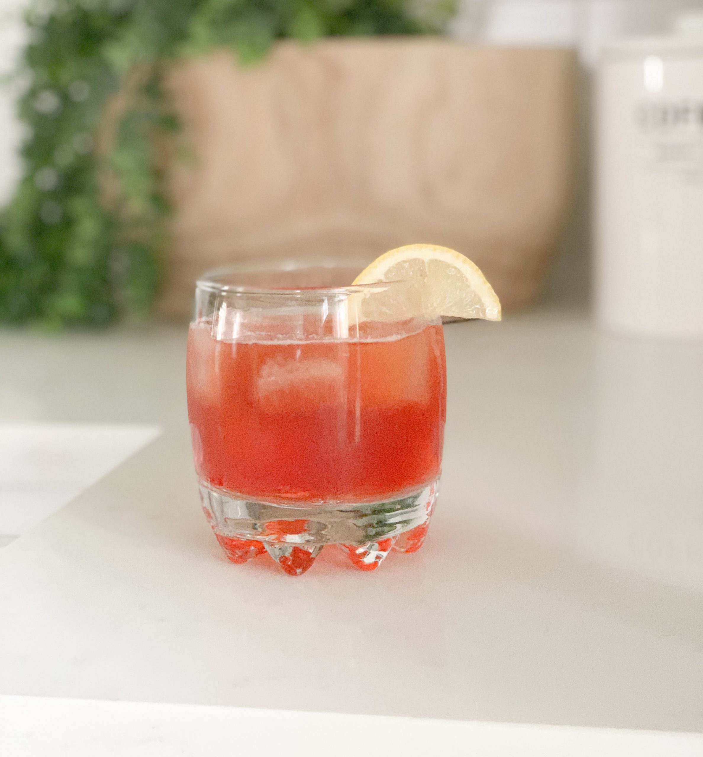 Amber Road Aperol Cocktail in a glass with a slice of lemon on the rim.