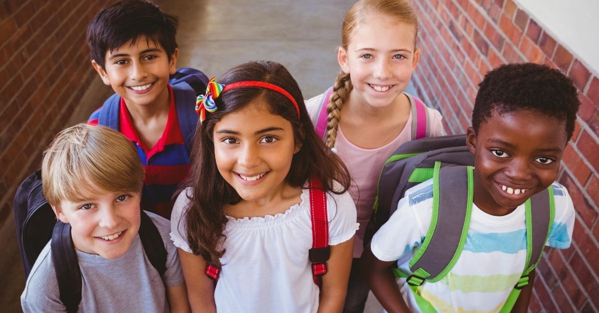 Having Kids Is It Worth It - picture of diverse kids with backpacks smiling at camera