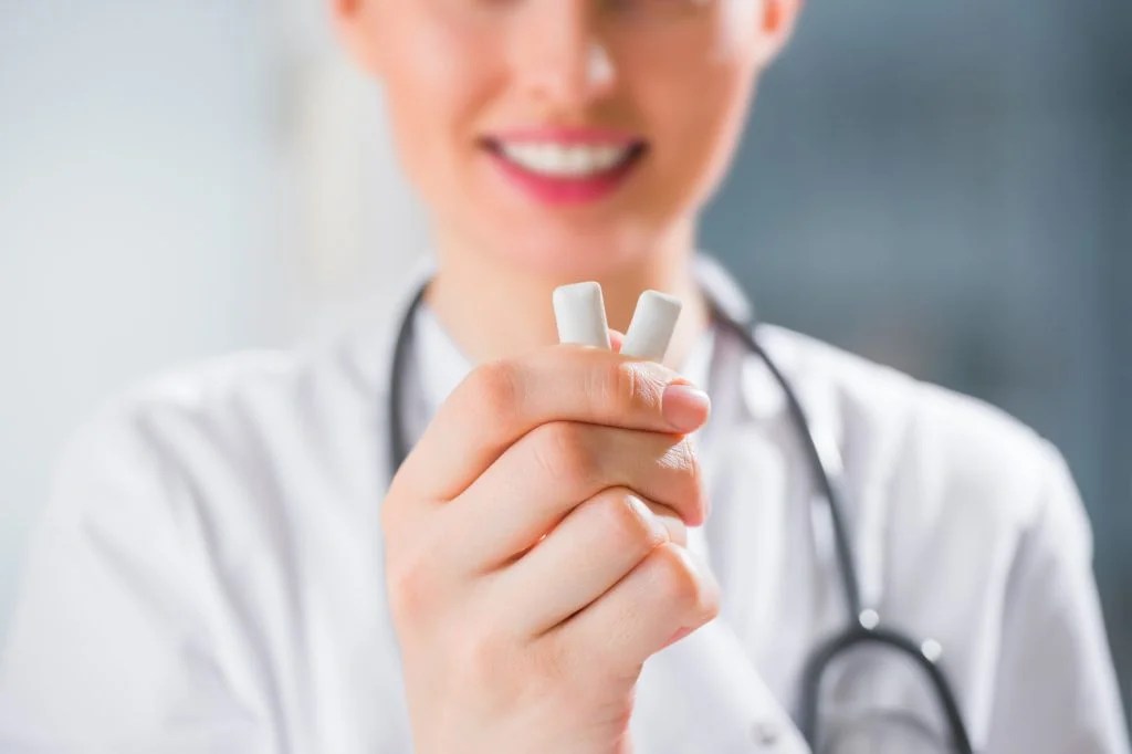 Female medical doctor dentist showing chewing gum. Dental ca