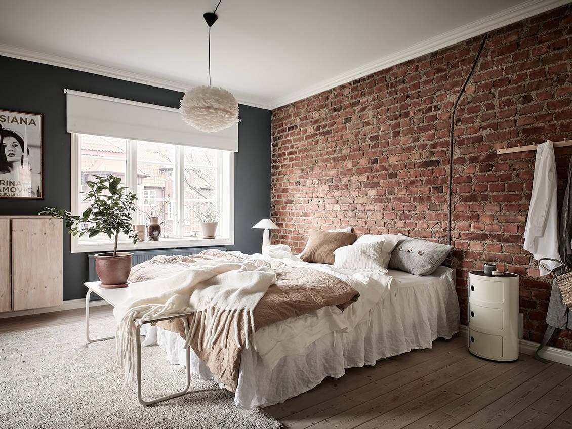 Blue bedroom with an exposed brick wall COCO LAPINE DESIGNCOCO LAPINE