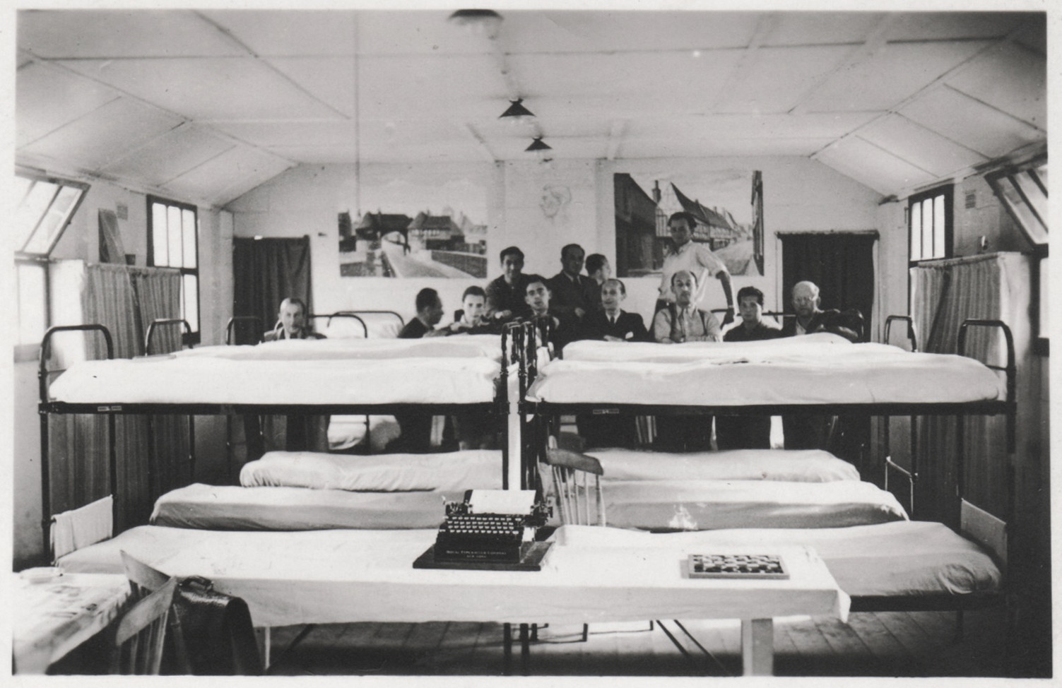 Jewish refugees pose behind their bunk beds in a barracks in the